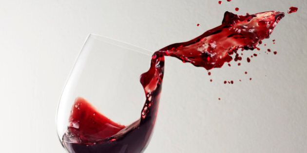 Glass of red wine spilling