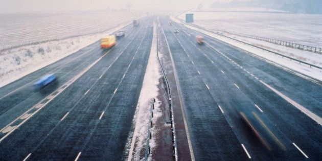 Motorway in winter, clear lanes surrounded by snow, elevated view