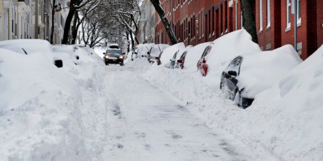 A car makes its way down a street filled with snowed-in vehicles in Boston's Charlestown section, Wednesday, Jan. 28, 2015 one day after a blizzard dumped about two feet of snow in the city. Residents of Massachusetts woke up Wednesday to cars buried in several feet of snow, and secondary roads that remain covered. (AP Photo/Elise Amendola)
