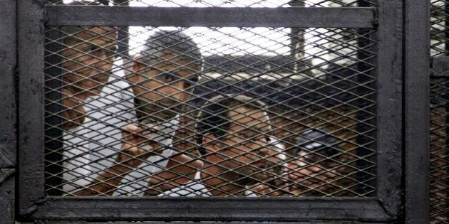 From left, Australian correspondent Peter Greste, Canadian-Egyptian acting bureau chief of Al-Jazeera Mohamed Fahmy, and Egyptian producer Baher Mohammed, appear in a defendant's cage in a courtroom in Cairo, Egypt, Monday, June 23, 2014. An Egyptian court on Monday convicted three journalists from Al-Jazeera English and sentenced them to seven years in prison each on terrorism-related charges, bringing widespread criticism that the verdict was a blow to freedom of expression. The three, Greste, Fahmy and Mohammed, have been detained since December charged with supporting the Muslim Brotherhood, which has been declared a terrorist organization, and of fabricating footage to undermine Egypt's national security and make it appear the country was facing civil war. (AP Photo/Heba Elkholy, El Shorouk Newspaper) EGYPT OUT