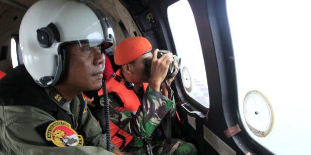 Crew members of Indonesian Air Force NAS 332 Super Puma helicopter look out of the windows during a search operation for the victims of AirAsia Flight 8501 over Kumai Bay, Indonesia, Friday, Jan. 2, 2015. More ships arrived Friday with sensitive equipment to hunt for the fuselage of AirAsia Flight 8501 and the more than 145 people still missing since it crashed into the sea five days ago. (AP Photo/Bagus Indahono, Pool)