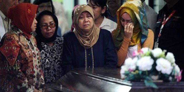 SURABAYA, INDONESIA - JANUARY 01: Hayati Lutfiah Hamid's (C), the mother of the first identified victim of the AirAsia flight QZ8501, cries during a handover ceremony from AirAsia to her family on January 1, 2015 in Surabaya, Indonesia. A massive recovery operation is underway in waters off Borneo to recover bodies and debris from the missing AirAsia plane. AirAsia announced that flight QZ8501 from Surabaya to Singapore, with 162 people on board, lost contact with air traffic control at 07:24 a.m. local time on December 28. (Photo by Robertus Pudyanto/Getty Images)
