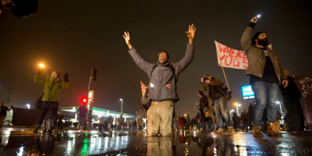 Anthony Grimes kneels on a rain-soaked street as he blocks traffic with other protesters Sunday, Nov. 23, 2014, in St. Louis. Ferguson and the St. Louis region are on edge in anticipation of the announcement by a grand jury whether to criminally charge officer Darren Wilson in the killing of 18-year-old Michael Brown. (AP Photo/David Goldman)