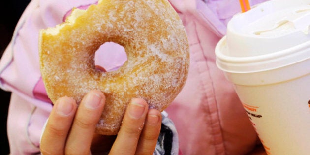 FILE - In this Feb. 14, 2013 file photo, a girl holds a beverage, served in a foam cup, and a donut at a Dunkin' Donuts in New York. The New York City Council's sanitation committee has a hearing set for Monday, Nov. 25, 2013, on proposals to ban plastic-foam food containers or explore recycling them. (AP Photo/Mark Lennihan, File)