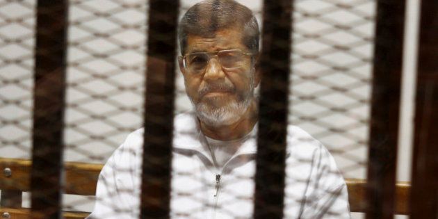 FILE - In this May 8, 2014 file photo, Egypt's ousted Islamist President Mohammed Morsi sits in a defendant cage in the Police Academy courthouse in Cairo, Egypt. On Tuesday April 21, 2015, an Egyptian criminal court sentenced Morsi to 20 years in prison over the killing of protesters in 2012, the first verdict to be issued against the leader. The case stems from violence outside the presidential palace in December 2012. (AP Photo/Tarek el-Gabbas, File)