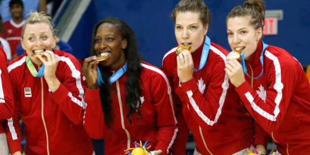 Canada's Lizanne Murphy, left, Tamara Tatham, center left, and twin sisters Katherine Plouffe, center right, and Michelle Plouffe pose for photographers with their gold medals during the women's basketball medal ceremony at the Pan Am Games, Monday, July 20, 2015, in Toronto. (AP Photo/Julio Cortez)
