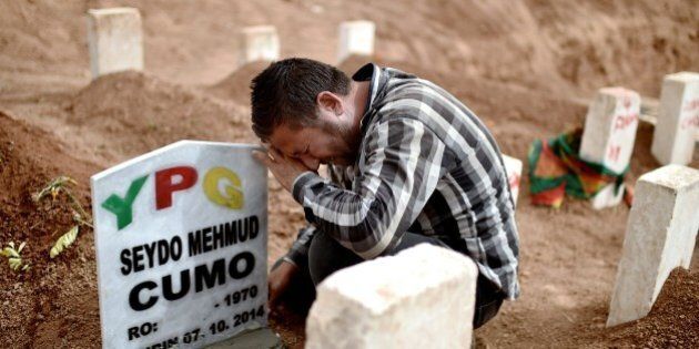 The brother of Syrian Kurdish People's Protection Units (YPG) militant Seydo Mehmud mourn above his grave on October 11, 2014 in the Turkish town of Suruc, Sanliurfa province, during the funeral of YPG militants fighting against Islamic State (IS) group jihadists for the control of the mainly-Kurdish Syrian town of Ain al-Arab, known as Kobane by the Kurds. Turkey has tightened security of its porous Syrian border after the escalating fighting in Ain al-Arab sparked the exodus of 200,000 refugees across the frontier. AFP PHOTO / ARIS MESSINIS (Photo credit should read ARIS MESSINIS/AFP/Getty Images)