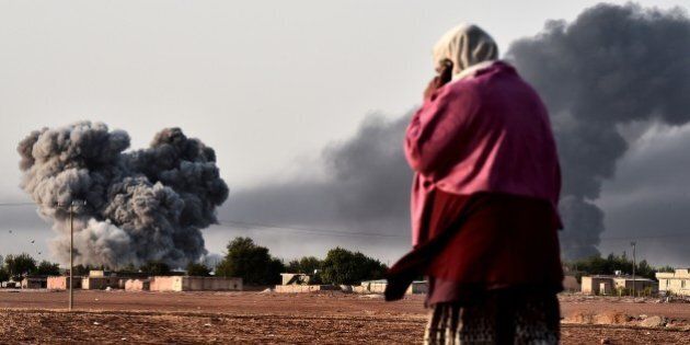 A woman watches as smoke rises after a strike from the US-led coalition on the the Syrian town of Ain al-Arab, known as Kobane by the Kurds, as seen from the Turkish-Syrian border in the southeastern village of Mursitpinar, Sanliurfa province, on October 13, 2014. The US-led international coalition carried out at least two new air strikes against positions held by Islamic State militants (IS) in and around Kobane on October 13, as meanwhile fighting broke out between Islamist jihadists and Kurdish fighters close to the Turkish border just north of the besieged Syrian town of Kobane. AFP PHOTO / ARIS MESSINIS (Photo credit should read ARIS MESSINIS/AFP/Getty Images)