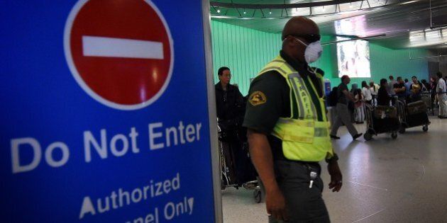 An airport worker wears a protective face mask in the arrivals area of the Los Angeles International Airport as the US announced increased passenger screenings against the Ebola Virus on October 9, 2014. Five United States airports (although not LAX) will step-up airport screening measures to look for passengers carrying Ebola, as the deadly virus killed a man in Texas and the worldwide toll neared 3,900. The spillover of the virus with the first diagnosis in United States and the first case of infection in Spain has raised fears of contagion in the West. AFP PHOTO/Mark RALSTON (Photo credit should read MARK RALSTON/AFP/Getty Images)