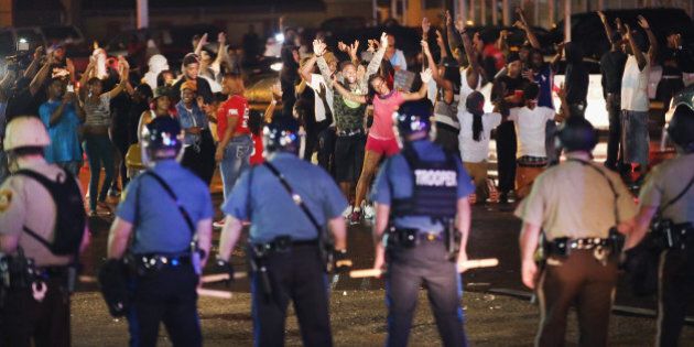 FERGUSON, MO - AUGUST 15: Missouri State Highway Patrol officers listen to taunts from demonstrators during a protest over the death of Michael Williams on August 15, 2014 in Ferguson, Missouri. As the taunts became more aggressive the troopers called in the county police then left the area. County police Shot pepper spray, smoke, gas and flash grenades at protestors before retreating. Several businesses were looted as the county police sat nearby with armored personnel carriers (APC). Violent outbreaks have taken place in Ferguson since the shooting death of Brown by a Ferguson police officer on August 9. (Photo by Scott Olson/Getty Images)
