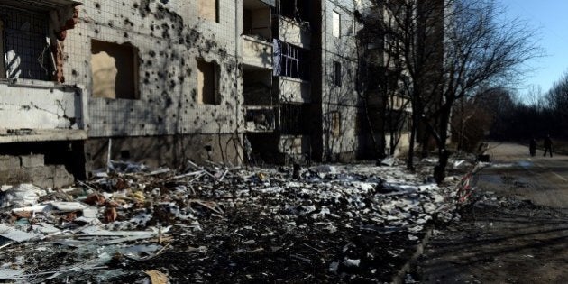 Pedestrians walk past a damaged building in Donetsk, on February 12, 2015. Russian President Vladimir Putin said that he and the leaders of France, Germany and Ukraine had agreed on the withdrawal of heavy weapons from Ukraine's frontlines and a ceasefire to begin from February 15. AFP PHOTO / VASILY MAXIMOV (Photo credit should read VASILY MAXIMOV/AFP/Getty Images)