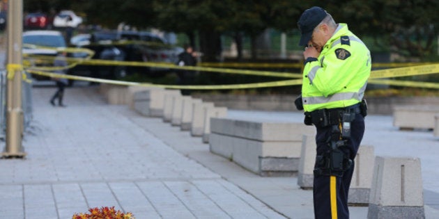 OTTAWA, ON- OCTOBER 23 - A RCMP officer looks at floral tributes to Cpl. Nathan Cirillo. Police continue to investigate in the aftermath of a shooting in Ottawa, where a soldier murdered at the War Memorial and a gun battle in Parliament killed the alleged gun man. in Ottawa. October 23, 2014. (Steve Russell/Toronto Star via Getty Images)