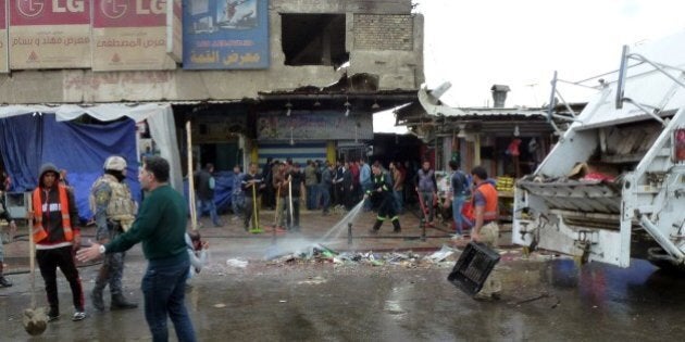 Iraqi's clean the street after a suicide bomber detonated explosives inside a restaurant in Baghdad al-Jadida, east of the capital, on February 7, 2015. Bombings in the Iraqi capital killed at least 17 people, hours before a years-old nightly curfew is due to be lifted, officials said. AFP PHOTO/SABAH ARAR (Photo credit should read SABAH ARAR/AFP/Getty Images)