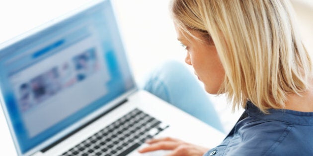 Pretty Caucasian woman browsing internet on laptop