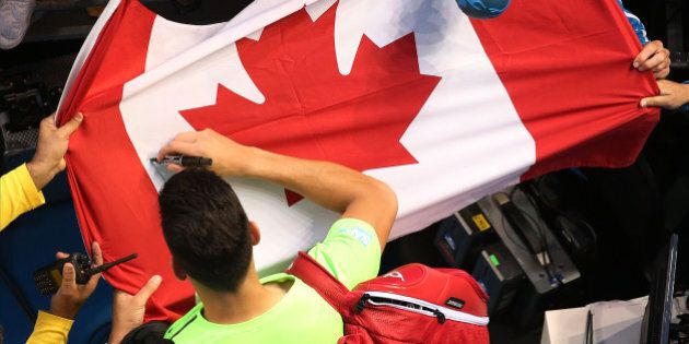 MELBOURNE, AUSTRALIA - JANUARY 26: Milos Raonic of Canada signs a Canadian flag after winning his fourth round match against Feliciano Lopez during day eight of the 2015 Australian Open at Melbourne Park on January 26, 2015 in Melbourne, Australia. (Photo by Michael Dodge/Getty Images)