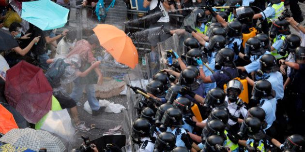 Riot police use pepper spray against protesters after thousands of people block a main road to the financial central district outside the government headquarters in Hong Kong, Sunday, Sept. 28, 2014. A tense standoff between thousands of Hong Kong pro-democracy protesters and police warning of a crackdown spiraled into an extraordinary scene of chaos Sunday as the crowd jammed a busy road and clashed with officers wielding pepper spray. (AP Photo/Vincent Yu)