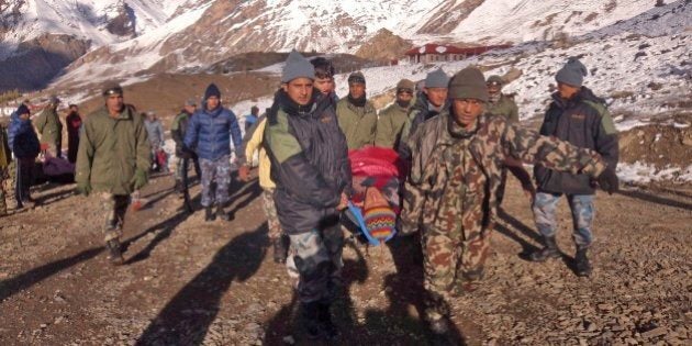 In this photo provided by the Nepalese army, soldiers carry an avalanche victim before he is airlifted in Thorong La pass area, Nepal, Wednesday, Oct. 15, 2014. An avalanche and blizzard in Nepal's mountainous north have killed at least 12 people, including eight foreign trekkers, officials said Wednesday. Five other climbers were hit by a separate avalanche on Mount Dhaulagiri and remain missing. (AP Photo/Nepalese Army)