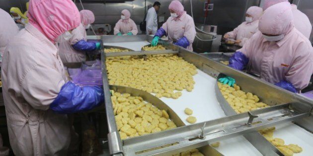 This picture taken on July 20, 2014 shows workers producing food at the Shanghai Husi Food Co., a factory of US food provider OSI Group, in Shanghai. Shanghai city officials have shut a Shanghai Husi factory of US food provider OSI Group for selling out-of-date meat to restaurant giants including McDonald's and KFC, authorities said on July 21 in China's latest food safety scandal. CHINA OUT AFP PHOTO (Photo credit should read STR/AFP/Getty Images)