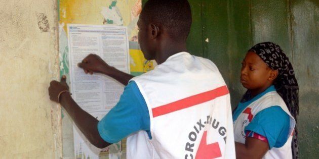 Members of the Guinean Red Cross stick information concerning the Ebola virus during an awareness campaign on April 11, 2014 in Conakry. Guinea has been hit by the most severe strain of the virus, known as Zaire Ebola, which has had a fatality rate of up to 90 percent in past outbreaks, and for which there is no vaccine, cure or even specific treatment. The World Health Organization (WHO) has described west Africa's first outbreak among humans as one of the most challenging since the virus emerged in 1976 in what is now the Democratic Republic of Congo. AFP PHOTO / CELLOU BINANI (Photo credit should read CELLOU BINANI/AFP/Getty Images)