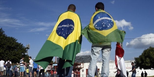 People wearing Brazilian flags arrive at the Santa Cruz Stadium in Ribeirao Prato to attend a France's national football team training session on June 10, 2014, a few days prior to the start of the 2014 FIFA World Cup in Brazil. AFP PHOTO / FRANCK FIFE (Photo credit should read FRANCK FIFE/AFP/Getty Images)