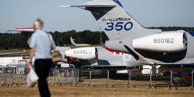 A visitor passes a Bombardier Challenger 350 business aircraft, produced by Bombardier Inc., as it stands on display on the first day of the Farnborough International Air Show in Farnborough, U.K., on Monday, July 14, 2014. The Farnborough International Air Show, which runs July 14-20, is this year's biggest forum for aircraft introductions and sales. Photographer: Simon Dawson/Bloomberg via Getty Images