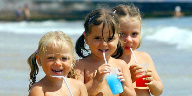 (Left to right): Finn family sisters Maisie, 2, and twins Mollie and Millie, 3, from Bournemouth, cool down with iced drinks at Bournemouth beach in Dorset, as weather forecasters predicted the hottest July day since 1911.