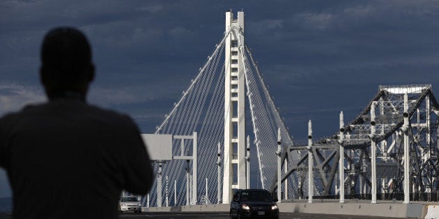 SAN FRANCISCO, CA - SEPTEMBER 02: A California Highway Patrol officer looks on as a procession of cars crosses the new eastern span of the San Francisco Oakland Bay Bridge following a chain-cutting ceremony to mark the opening of the bridge on September 2, 2013 in San Francisco, California. After nearly 12 years of construction and an estimated price tag of $6.4 billion, the new eastern span of the Bay Bridge will open to traffic a day ahead of schedule. The bridge will be the world's tallest Self-Anchored Suspension (SAS) tower once completed. (Photo by Justin Sullivan/Getty Images)