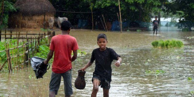 GUWAHATI, INDIA - 2014/08/17: Indian boys walk through a flood water at Amoni in Nagaon, 180km East of Guwahati. Due to heavy rainfall in India's North-Eastern states of Arunachal Pradesh and Assam, several districts were submerged, affecting over 150,000 people. (Photo by Stringer/Pacific Press/LightRocket via Getty Images)