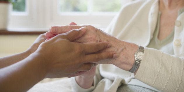 Close up of older woman and caretaker holding hands