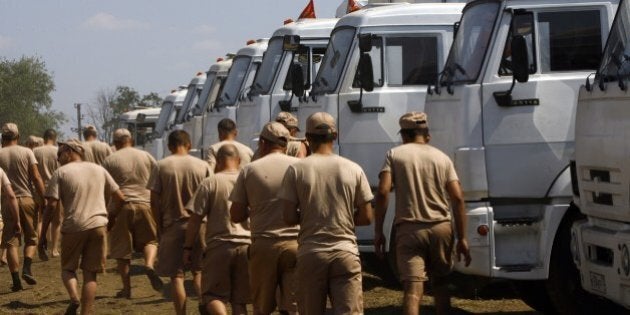 Drivers walks past the Russian humanitarian convoy trucks parked on a field outside the town of Kamensk-Shakhtinsky in the Rostov region, some 30kms from the Russian-Ukrainian border, Russia, on August 14, 2014. A massive Russian 'humanitarian' convoy closed in on Ukraine's border today despite doubts over whether the trucks would be allowed across, and as deadly fighting rocked rebel-held strongholds. The nearly 300 vehicles headed towards southeastern Ukraine, even as intense shelling there in the insurgent bastions of Donetsk and Lugansk -- where the trucks appear headed -- sharply increased the death toll from fighting. AFP PHOTO / ANDREY KRONBERG (Photo credit should read ANDREY KRONBERG/AFP/Getty Images)