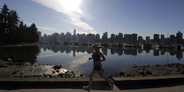 A woman joggs in Stanley Park in front of the Vancouver Skyline on February 19, 2010, during the Vancouver Winter Olympics. AFP PHOTO DDP / DAVID HECKER (Photo credit should read DAVID HECKER/AFP/Getty Images)