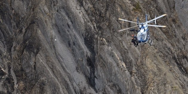 A helicopter carries investigators near scattered debris on the crash site of the Germanwings Airbus...