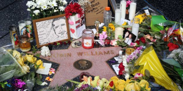 Flowers, photographs and candles surround the star of actor-comedian Robin Williams forming a makeshift memorial along the Hollywood Walk of Fame in Los Angeles on Tuesday, Aug. 12, 2014. Williams, 63, died at his San Francisco Bay Area home Monday in an apparent suicide. (AP Photo/Nick Ut)