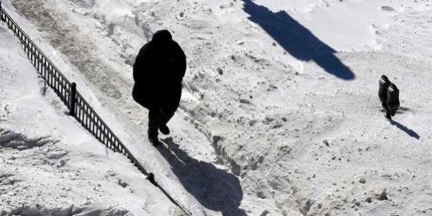 A man walks on a snow-covered sidewalk in Boston, Monday, Feb. 16, 2015. New England remained bitterly cold Monday after the region's fourth winter storm in a month blew through. (AP Photo/Michael Dwyer)