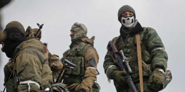 A Russia-backed rebel fighter holds a sniper rifle while a mask in Debaltseve, Ukraine, Friday, Feb. 20, 2015. After weeks of relentless fighting, the embattled Ukrainian rail hub of Debaltseve fell Wednesday to Russia-backed separatists, who hoisted a flag in triumph over the town. The Ukrainian president confirmed that he had ordered troops to pull out and the rebels reported taking hundreds of soldiers captive.(AP Photo/Vadim Ghirda)