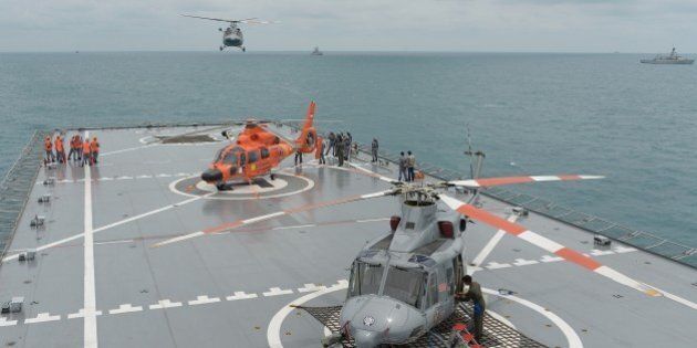 A navy helicopter arrives on the Indonesian navy vessel KRI Banda Aceh, close to area where search teams located the tail of AirAsia QZ8501 in the Java sea on January 8, 2015. Elite Indonesian military divers battled strong currents on Thursday in an effort to reach the submerged tail of crashed AirAsia Flight QZ8501 in the hopes of finding crucial black box data recorders. AFP PHOTO / POOL / ADEK BERRY (Photo credit should read ADEK BERRY/AFP/Getty Images)