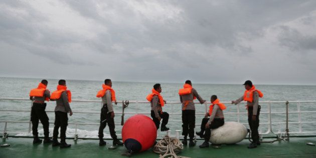 Indonesian police stand on the deck of a National Search And Rescue Agency (BASARNAS) ship during a search operation for the victims of AirAsia flight QZ 8501 on the Java Sea, Indonesia, Saturday, Jan. 3, 2015. Indonesian officials were hopeful Saturday they were honing in on the wreckage of the ill-fated jetliner after sonar equipment detected large objects on the ocean floor, one week after the plane went down in stormy weather. (AP Photo/Achmad Ibrahim)