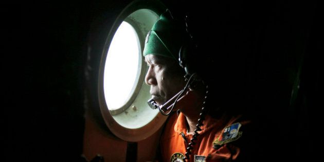 A crew of an Indonesian Air Force C-130 airplane of the 31st Air Squadron looks out of the window during a search operation for the missing AirAsia flight 8501 jetliner over the waters of Karimata Strait in Indonesia, Monday, Dec. 29, 2014. The Airbus A320-200 vanished Sunday morning in airspace thick with storm clouds on its way from Surabaya, Indonesia, to Singapore. (AP Photo/Dita Alangkara)