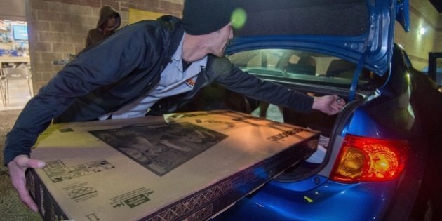 A Best Buy employee helps a customer load a new big screen TV into his car shortly after the Black Friday doorbuster sale started on Thursday, November 27, 2014 at 5:00pm in Fairfax, Virginia. Black Friday is a day of deep commercial discounts and frenzied shopping which takes place each year after the Thursday Thanksgiving holiday in the United States. AFP Photo/Paul J. Richards (Photo credit should read PAUL J. RICHARDS/AFP/Getty Images)