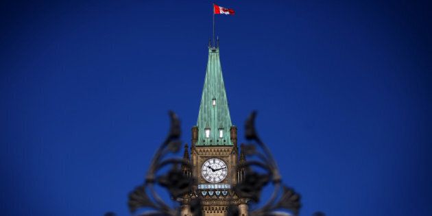 The Canadian flag flies above Parliament Hill in Ottawa, Ontario, Canada, on Tuesday, Feb. 11, 2014. Canadian Finance Minister Jim Flaherty ramped up efforts to return the country to surplus in a budget that raises taxes on cigarettes and cuts benefits to retired government workers while providing more aid for carmakers. Photographer: Cole Burston/Bloomberg via Getty Images