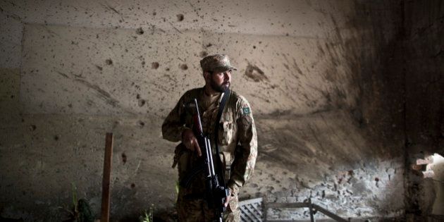 A Pakistani army officer, stands in front of a wall riddled with bullet marks, inside the Army Public School attacked last Tuesday by Taliban gunmen, in Peshawar, Pakistan, Thursday, Dec. 18, 2014. The Taliban massacre that killed more than 140 people, mostly children, at a military-run school in northwestern Pakistan left a scene of heart-wrenching devastation, pools of blood and young lives snuffed out as the nation mourned and mass funerals for the victims got underway. (AP Photo/Muhammed Muheisen)