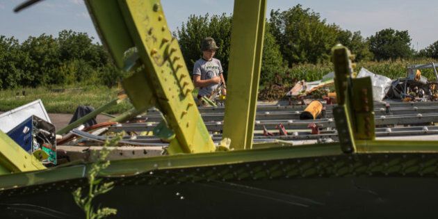 PETROPAVLIVKA, UKRAINE - JULY 24: Vlad, 10, looks at wreckage of the Malaysia Airlines flight MH17 that fell near his family's home on July 24, 2014 in Petropavlivka, Ukraine. Malaysian Airlines flight MH17 was travelling from Amsterdam to Kuala Lumpur when it crashed in eastern Ukraine killing all 298 passengers. The aircraft was allegedly shot down by a missile and investigations continue to find the perpetrators of the attack. (Photo by Rob Stothard/Getty Images)