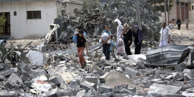 Palestinians carry their possessions as they walk on the rubble of buildings destroyed during the Israeli military offensive, close to the Rafah refugee camp, in southern Gaza Strip, on August 4, 2014. Civil defence workers and medics are searching the neighborhood looking for victims of the ongoing Israeli military operation which has killed some 1,829 Palestinians, mainly civilians. AFP PHOTO / MAHMUD HAMS (Photo credit should read MAHMUD HAMS/AFP/Getty Images)
