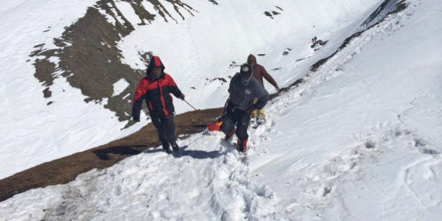 In this handout photo provided by the Nepalese army, rescue team members carry the body of an avalanche victim at Thorong La pass area in Nepal, Friday, Oct. 17, 2014. Rescuers widened their search Friday for trekkers stranded since a series of blizzards and avalanches battered the Himalayas in northern Nepal early this week, leaving at least 29 foreigners and locals dead, officials said. (AP Photo/Nepalese Army)