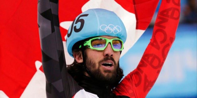 Charles Hamelin of Canada celebrates with the national flag after winning the men's 1500m short track speedskating final at the Iceberg Skating Palace during the 2014 Winter Olympics, Monday, Feb. 10, 2014, in Sochi, Russia. (AP Photo/Bernat Armangue)