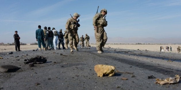 US soldiers, with Afghan policemen, inspect the site of a suicide attack targeting foreign troops in Jalalabad on November 13, 2014. A suicide bomber rammed his explosive-laden vehicle into an armoured vehicle of foreign forces in Jalalabad, the capital of eastern Nangarhar province on November 13, officials said. The attack caused no fatalities to foreign forces or civilians, but damaged an armoured vehicle. AFP PHOTO/Noorullah Shirzada (Photo credit should read Noorullah Shirzada/AFP/Getty Images)