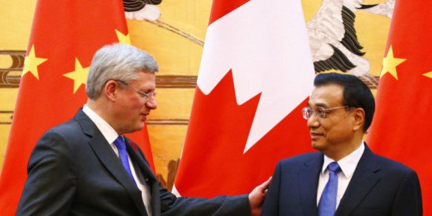 BEIJING, CHINA - NOVEMBER 08: China's Premier Li Keqiang (R) talks to Canada's Prime Minister Stephen Harper in front of the Chinese and Canadian national flags during a signing ceremony at the Great Hall of the People on November 8, 2014 in Beijing, China. The Canadian prime minister is on a four-day visit, aiming to build closer economic ties with Canadas No. 2 trading partner. (Photo by Petar Kujundzic - Pool/Getty Images)