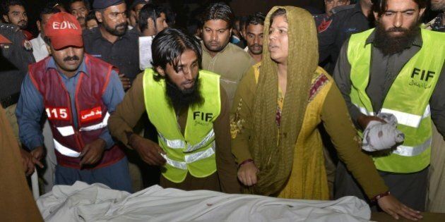 A Pakistani woman standing next to paramedics reacts over the body of a blast victim at a hospital after a suicide bomb attack near the Wagah border gate on November 2, 2014. A suicide bomber killed at least 55 people at the main Pakistan-India border crossing, the blast tearing through crowds of spectators leaving after the colourful daily ceremony to close the frontier. AFP PHOTO/ARIF ALI (Photo credit should read Arif Ali/AFP/Getty Images)