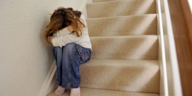 Young girl (6 years of age) sits on the landing of a staircase and covers her face. KEYWORDS: bullying, abused, abusing, abusive, aggression, aggressive, caucasian, afraid child cowering, child abuse, covering, defending, deflecting, face, depressed female, unhappy girl, hands, hitting, home, human, interpersonal, lifestyle, protecting, relationship, shielding, violence, violent, emotional stress, distress. (Photo by Jeff Overs/BBC News & Current Affairs via Getty Images)