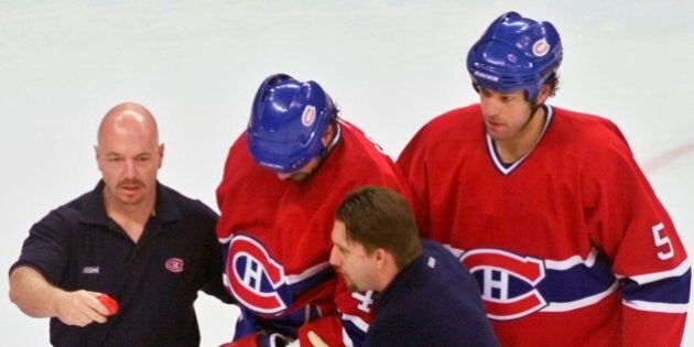 Montreal Canadiens' Sheldon Souray is taken from the ice by teammate Stephane Quintal (5) and team trainers after he was checked into the boards by Carolina Hurricanes' Jeff O'Neill during the first period of their second-round playoff game, Friday, May 3, 2002, at the Entertainment and Sports Arena, in Raleigh, N.C.(AP Photo/Karl DeBlaker)